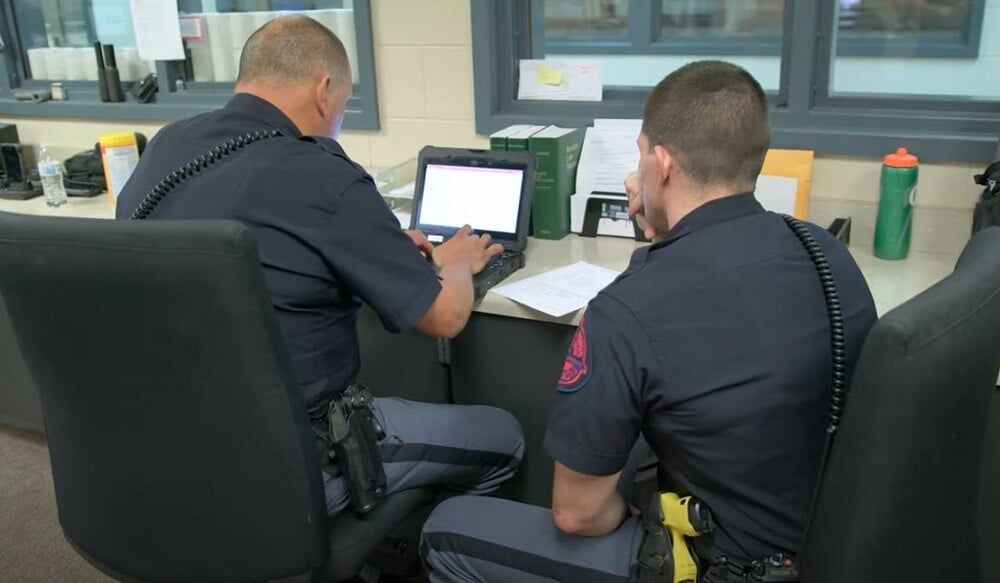 two corrections officers at laptop