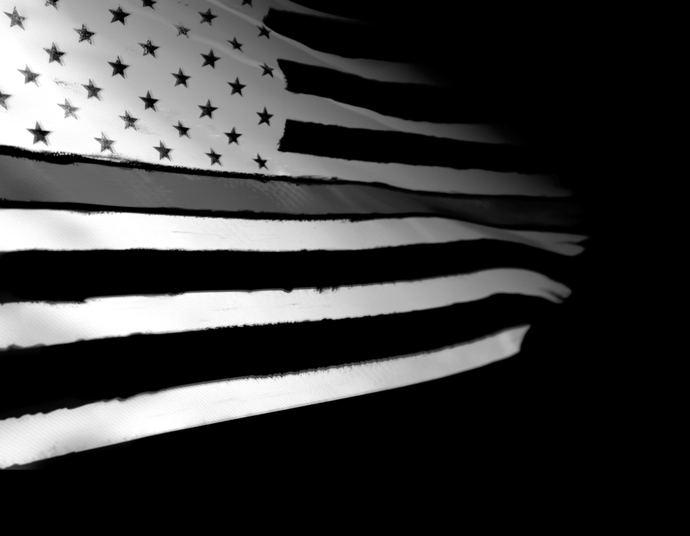 A tattered American flag lit from the side in black and white, its centre stripe reading as the Thin Gray Line that corrections officers hold
