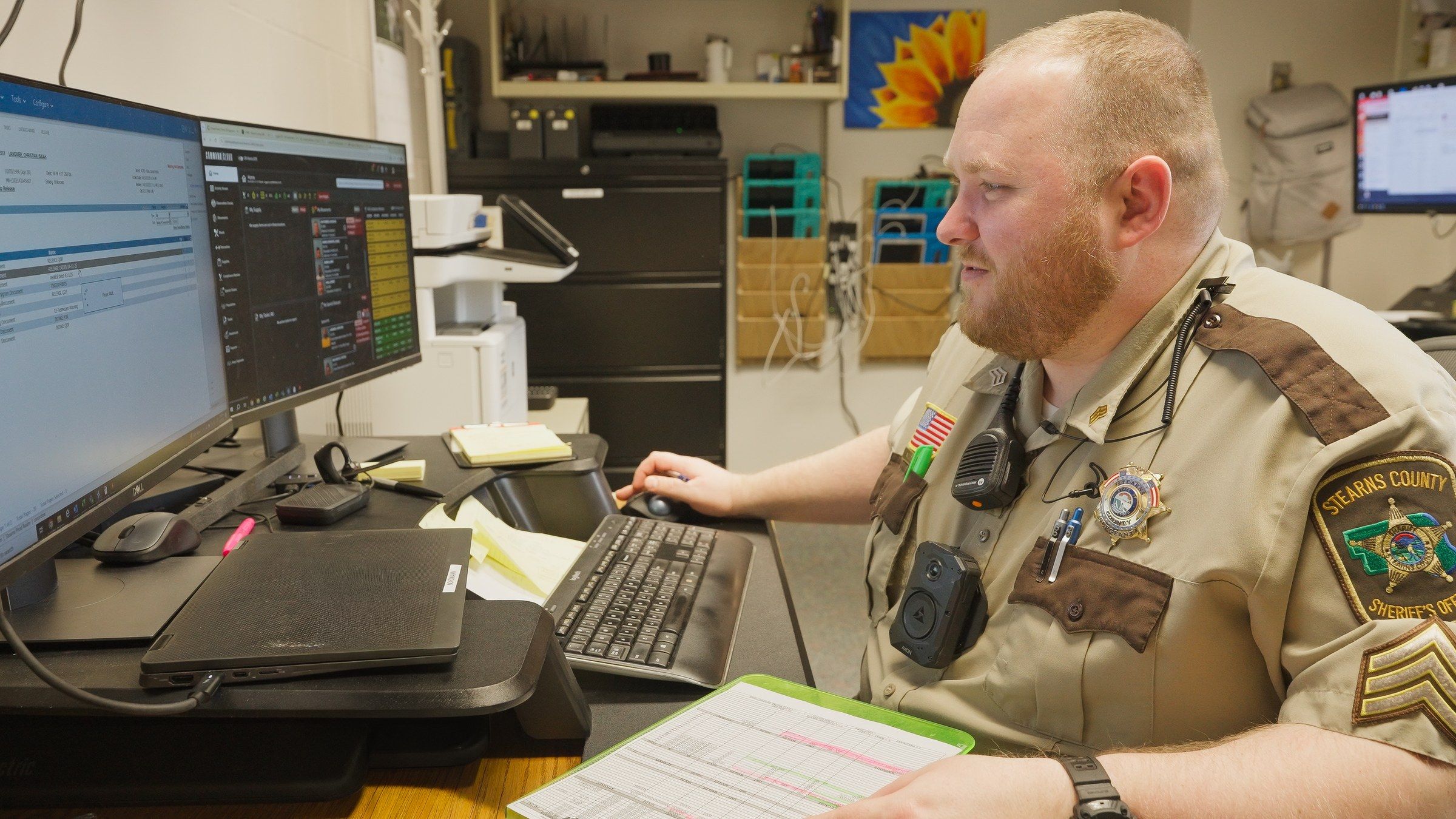 Correctional officer wearing a body camera reviewing GUARDIAN RFID records at a workstation