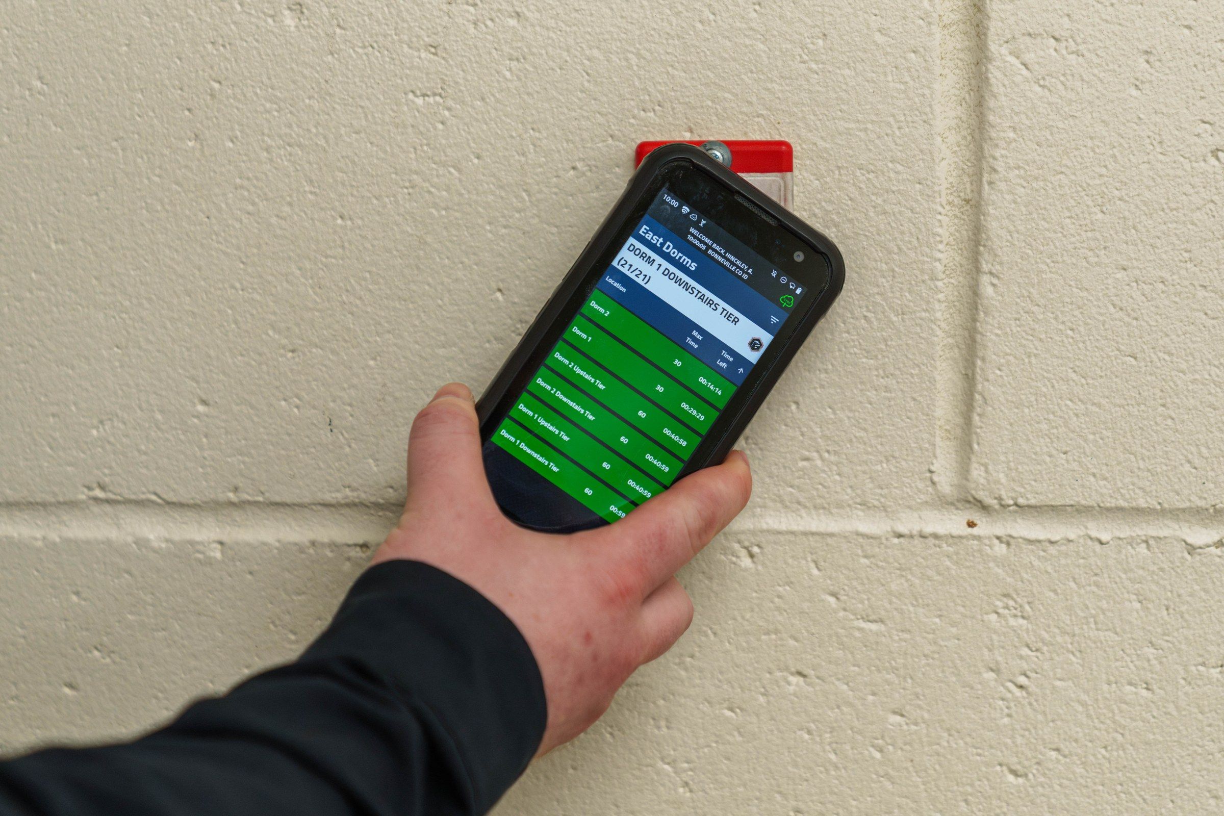 Officer completing a GUARDIAN RFID welfare check by scanning a housing-unit checkpoint