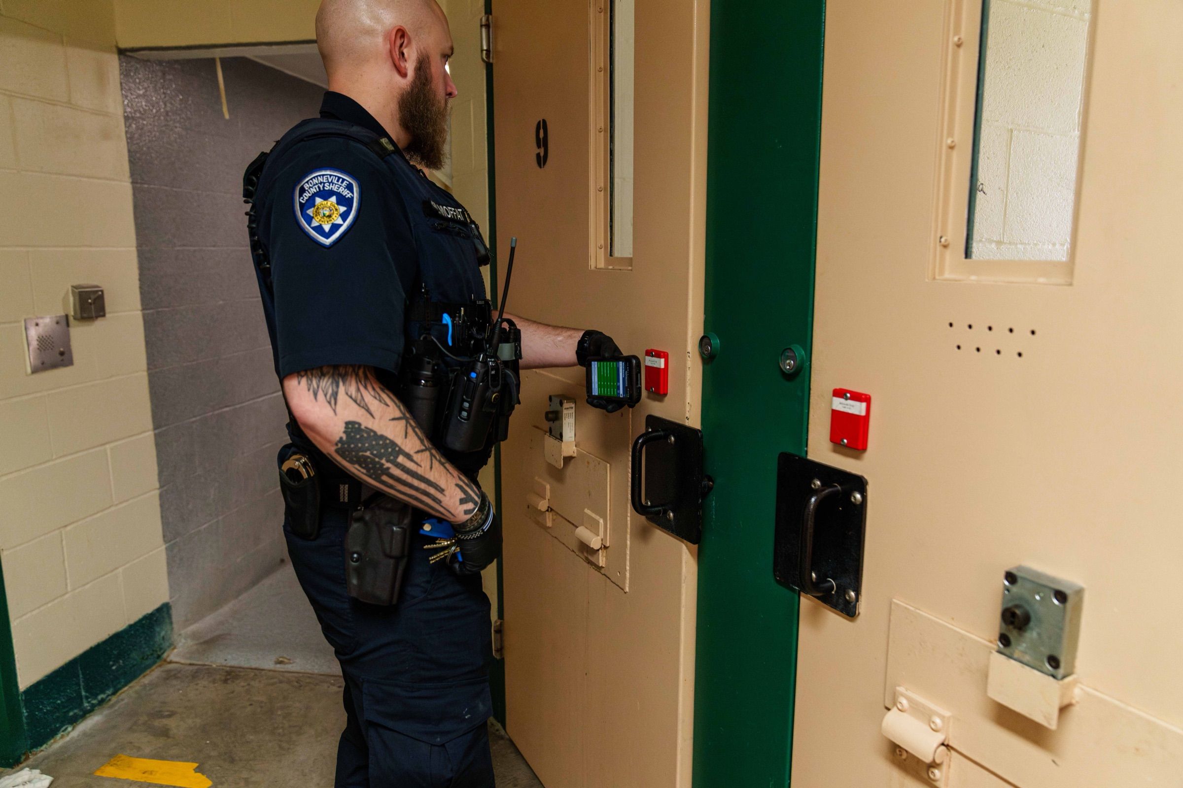 A corrections officer scanning an RFID tag at a cell door during a compliance check
