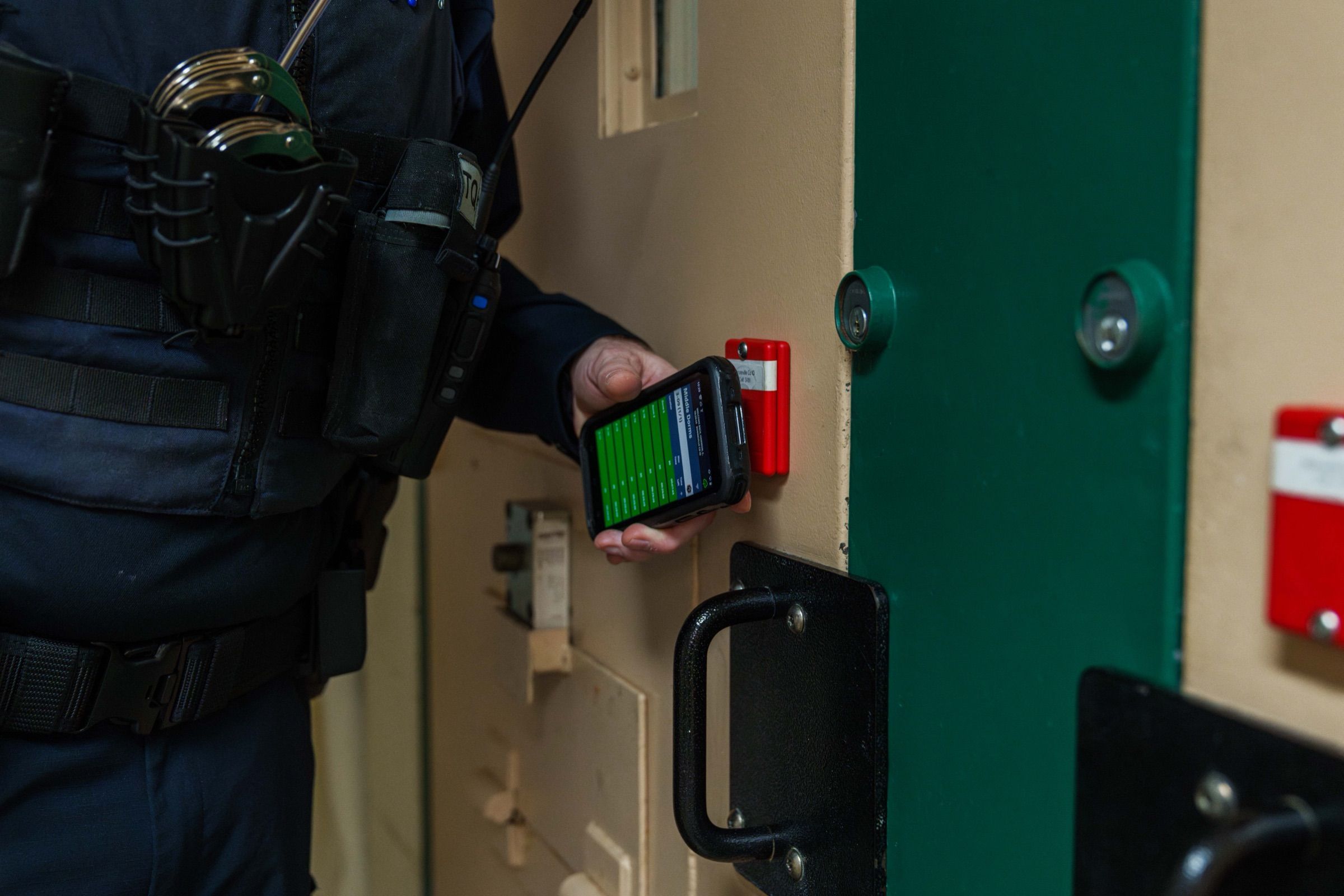 A corrections officer holding a SPARTAN handheld running Command Cloud during a cell check
