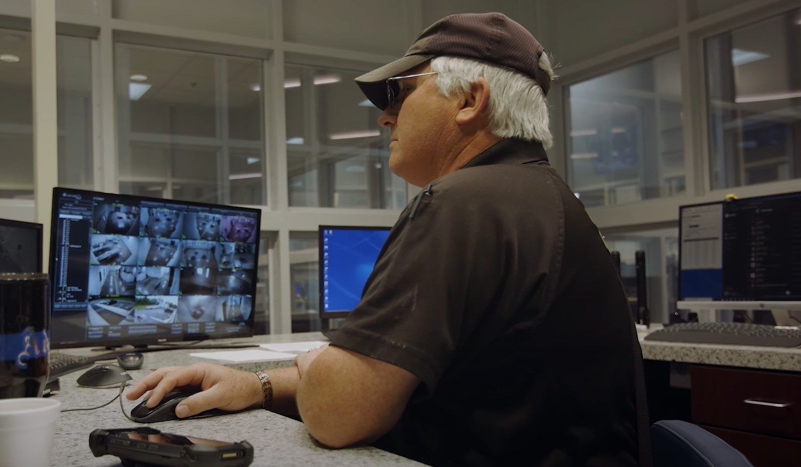 Correctional officer monitoring security camera feeds and Command Cloud on dual screens