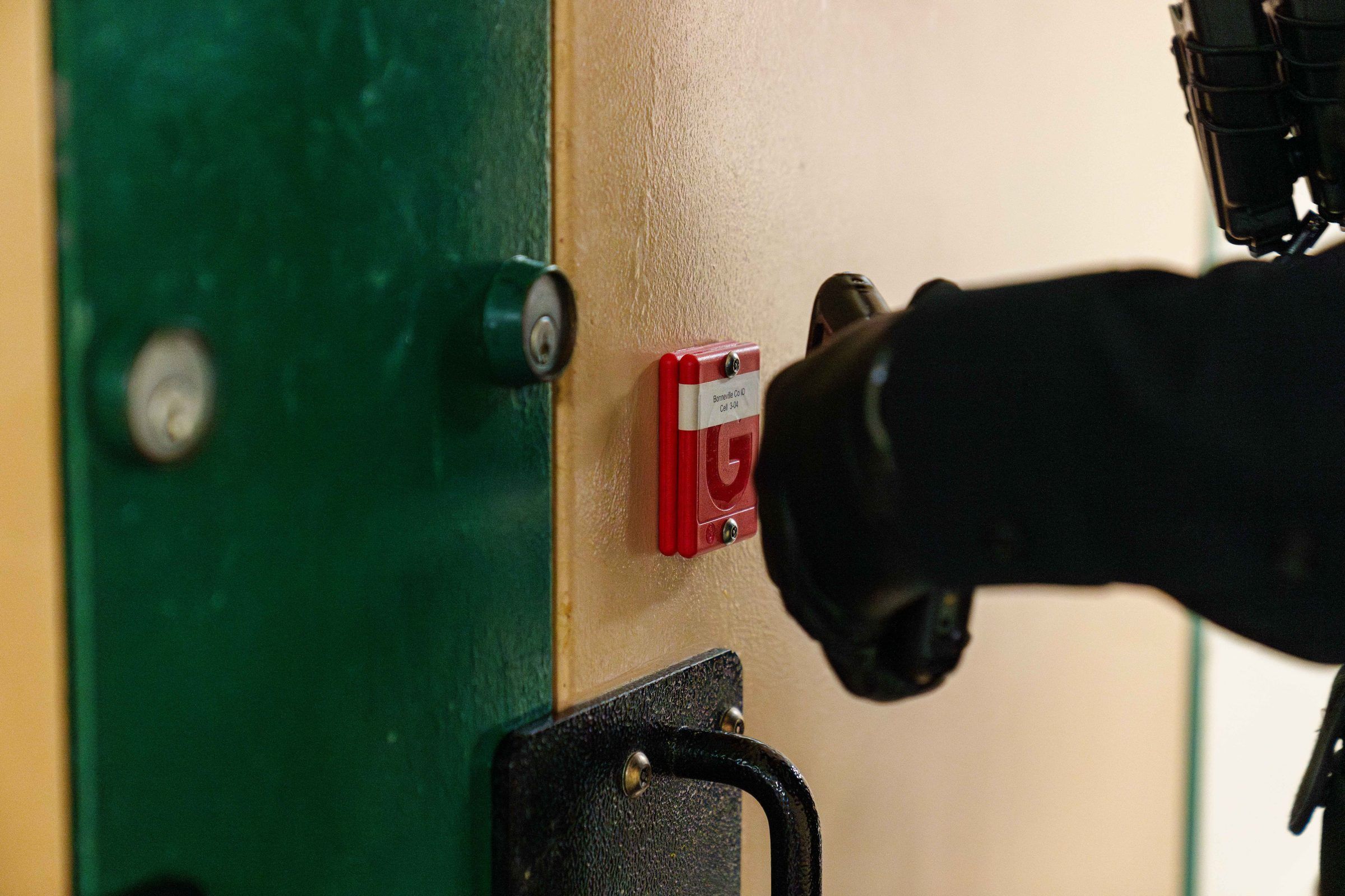 Officer holding a handheld at a cell door during rounds