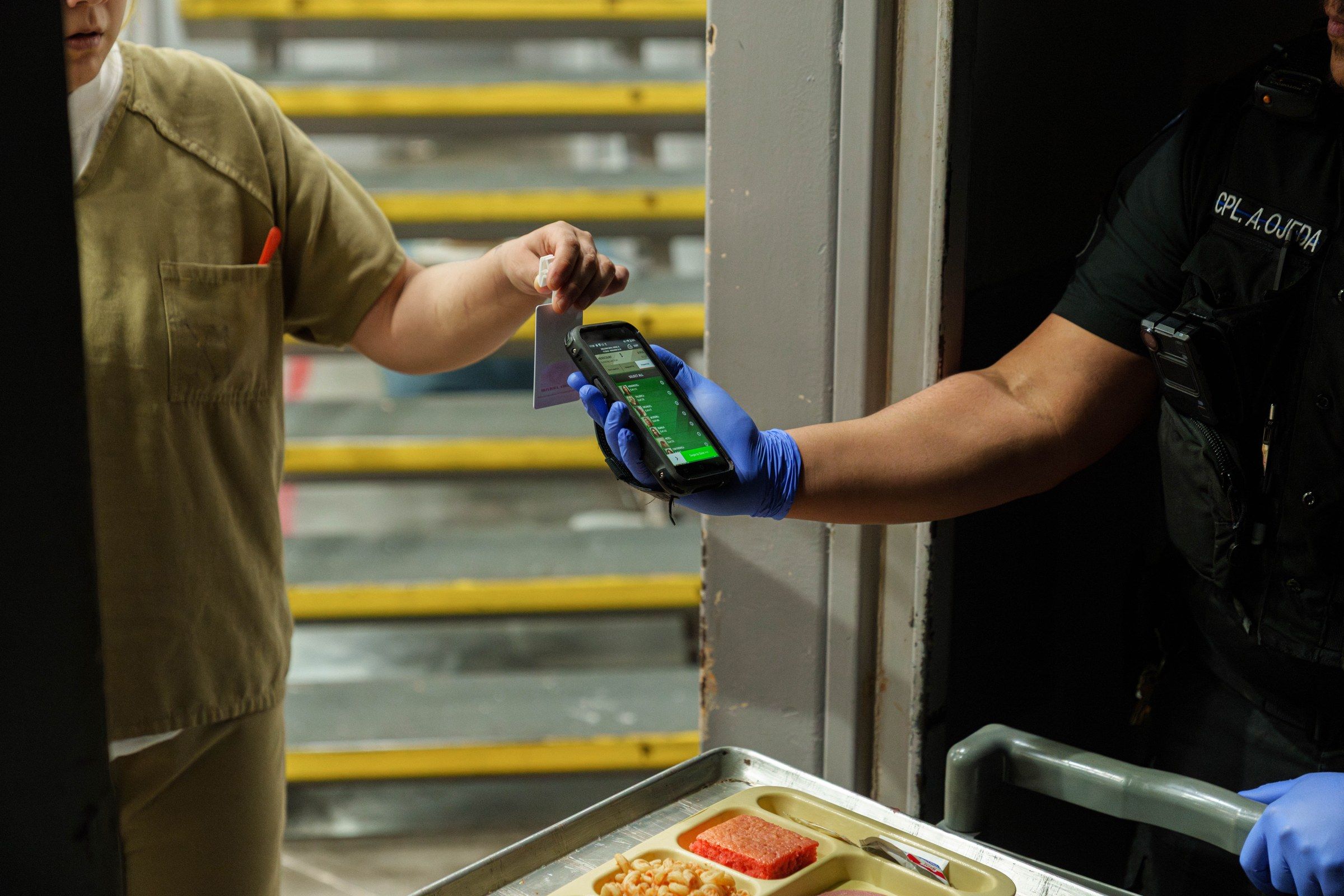 Corrections officer scanning inmate RFID cards at a cell door