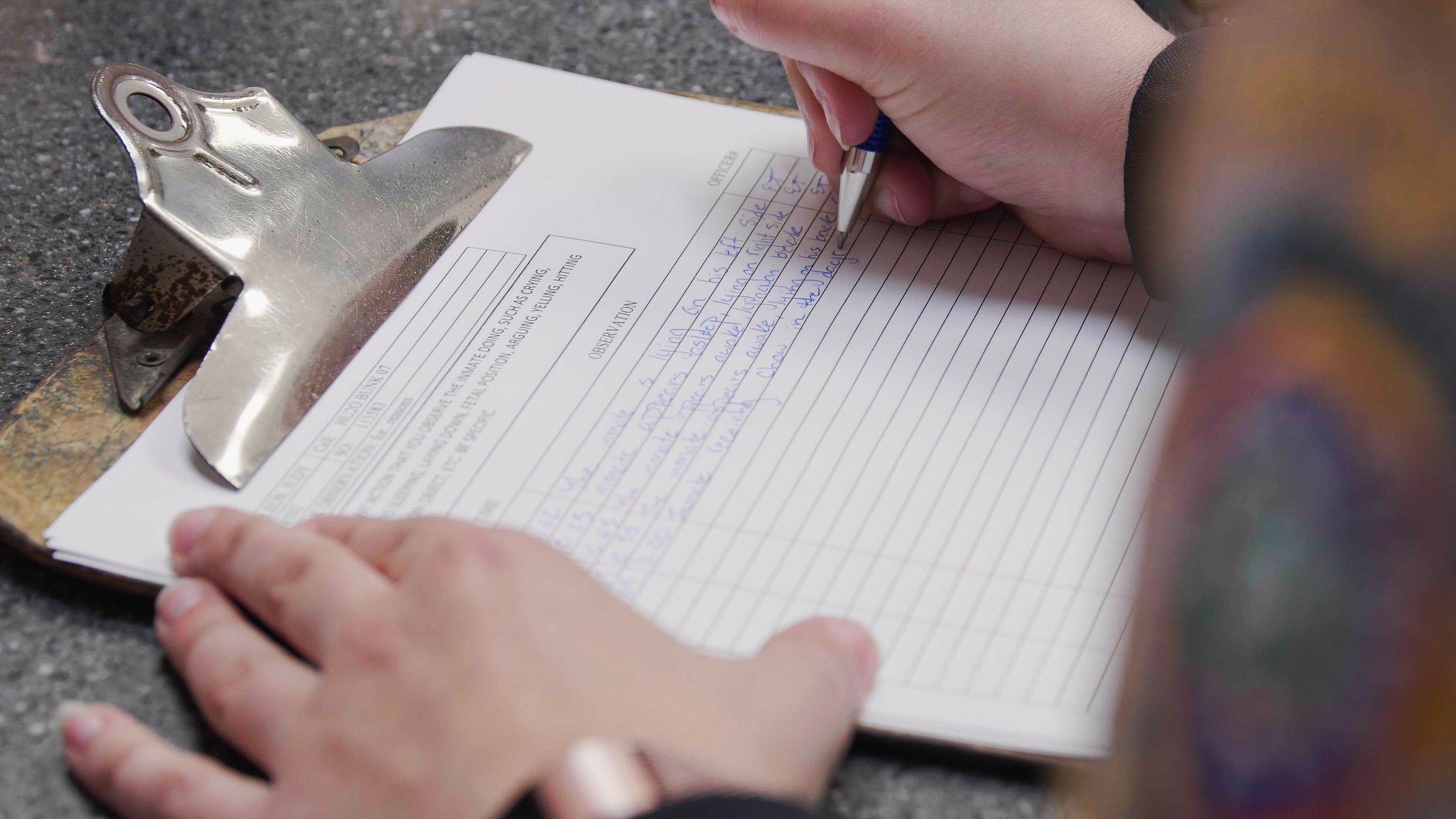 Handwritten correctional observation log beside stored paper jail record logbooks